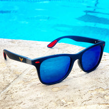 Load image into Gallery viewer, Poolside photo of black with red highlights sunglasses with polarized reflective blue lenses and the full Semper Fly logo on the frames.
